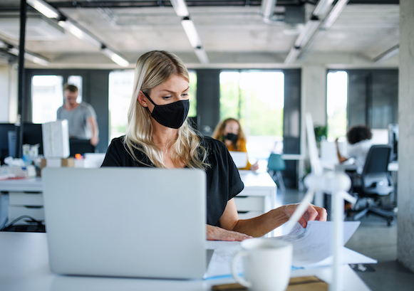 A woman at her office, wearing a mask