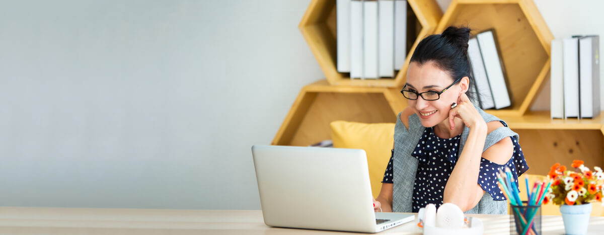 A woman smiling in front of her laptop