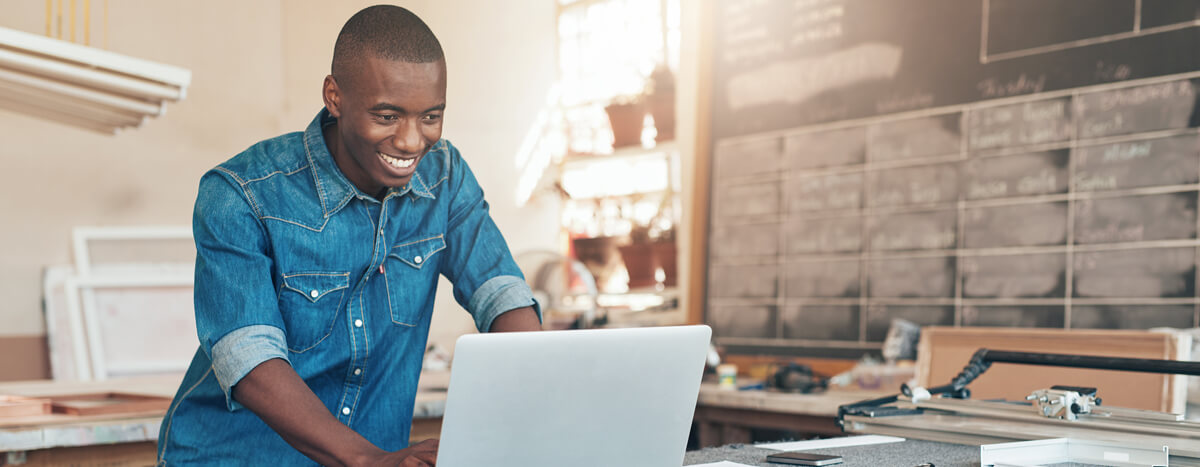 A guide smiling in front of his laptop in his kitchen