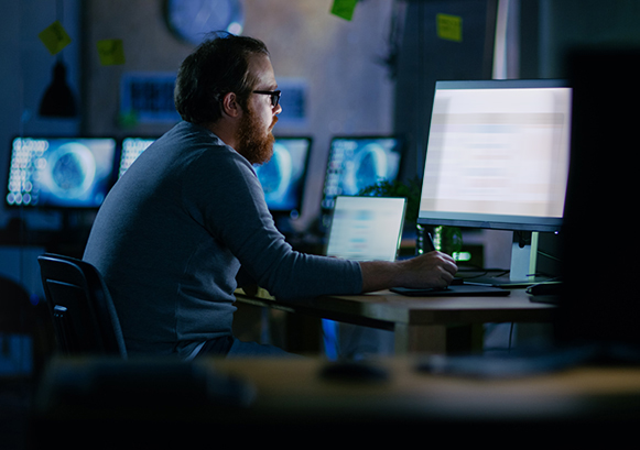 A guy working in front of his computer in the dark