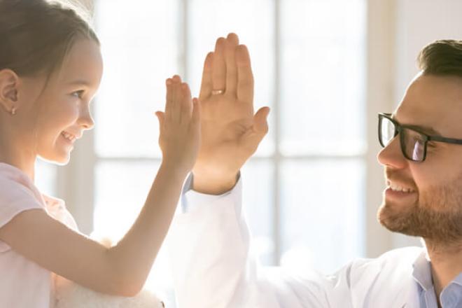 A young girl and a doctor clapping hands