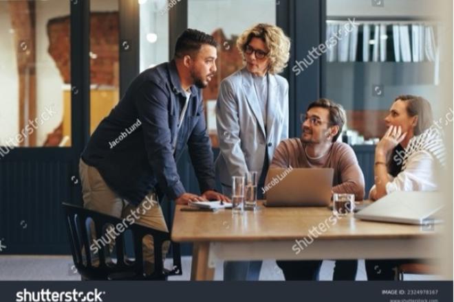 People collaborating around a table and in front of a laptop