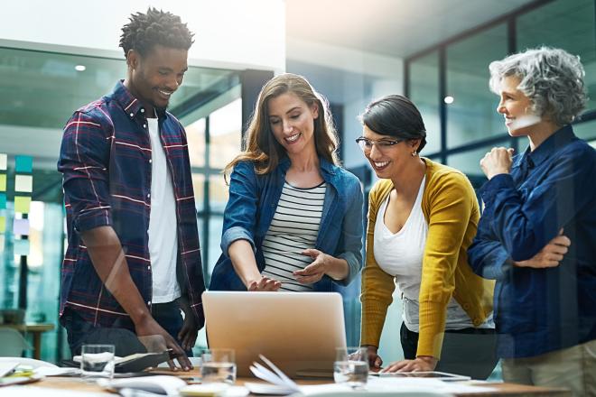 group of people talking and looking at a laptop