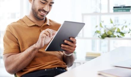 Man smiling and looking at a tablet