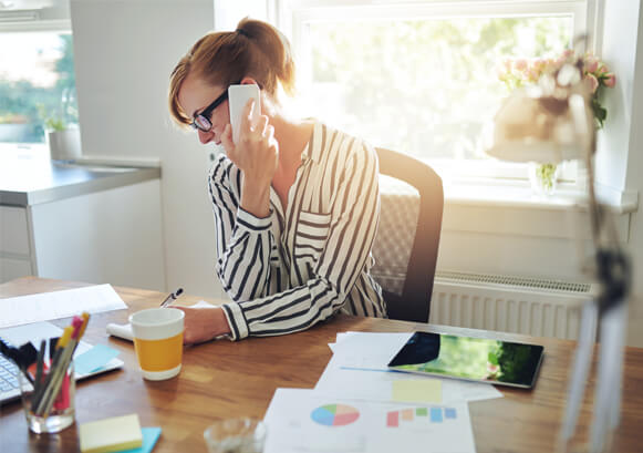 A woman on a call at her desk taking a note