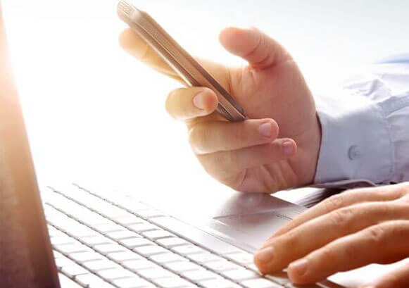 Someone in front of a keyboard looking at a phone