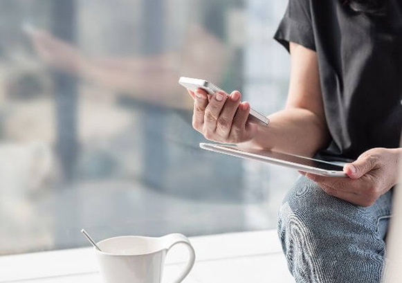 A woman looking at both a phone and a tablet
