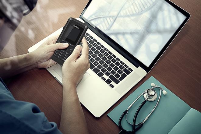 A guy looking at his phone on top of his laptop