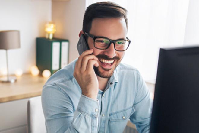 A guy in a phone call, laughing in front of his computer
