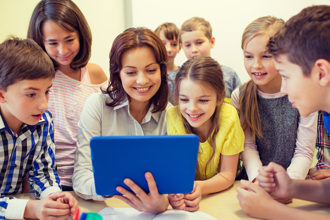 Kids and a teacher looking at a tablet