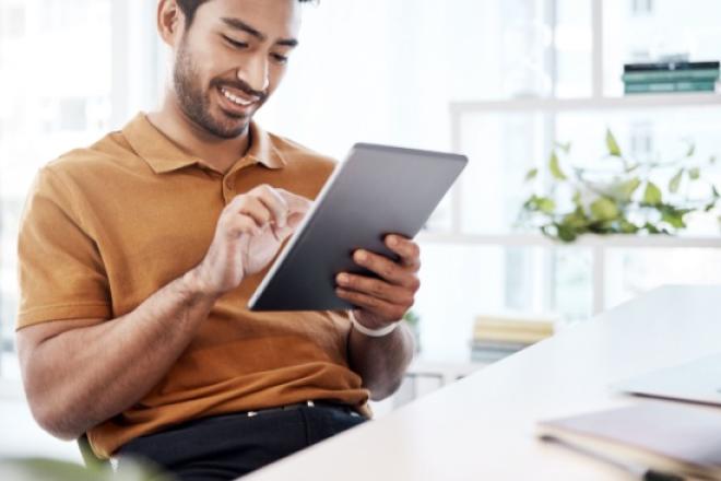 Man smiling and looking at a tablet