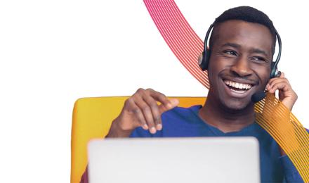 A guy smiling in front of his laptop with an headset