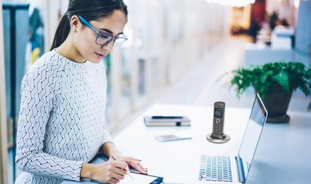 A woman working on her desk and taking notes