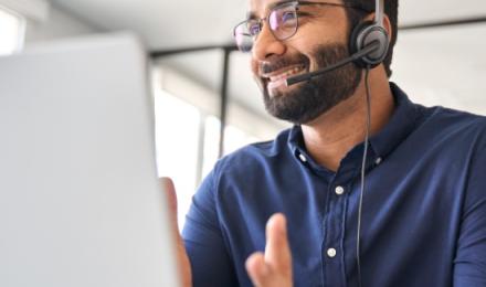 Une personne avec un casque discutant face a son ordinateur