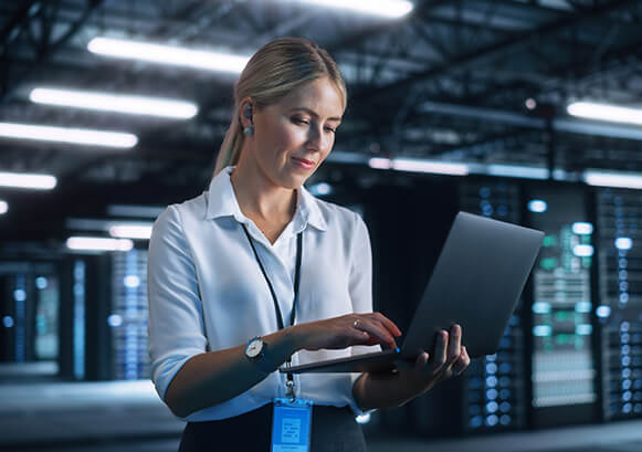 Woman using a laptop in a server room