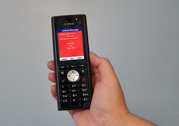 An hand holding a Mitel phone