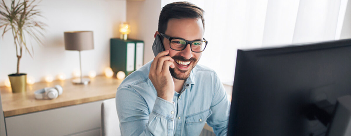 A guy in a phone call, laughing in front of his computer