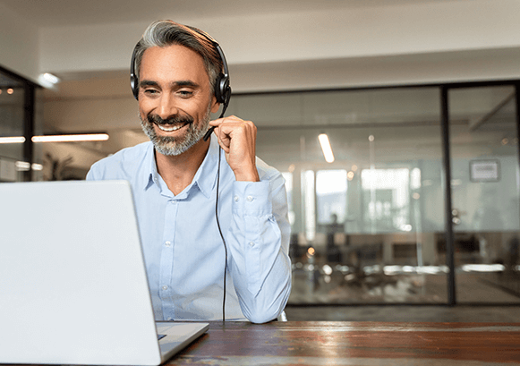 Man with a headset looking at his laptop and smiling