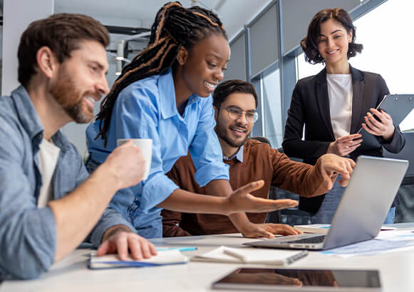 Four people collaborating in front of a laptop