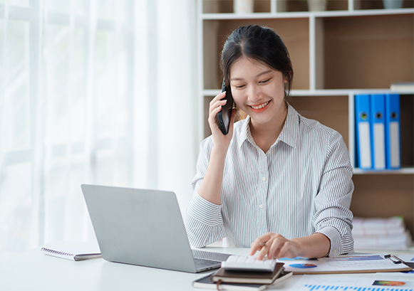 A woman on the phone in front of her laptop