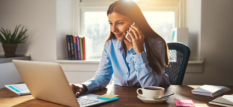 A woman on a phone call looking at her laptop