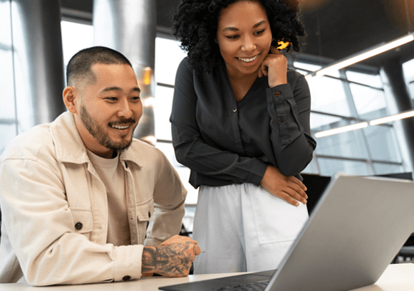 A woman and a man looking at the same screen and smiling