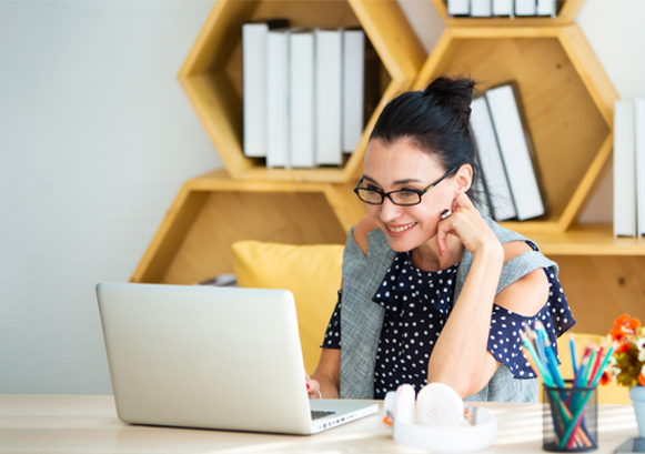 A woman smiling in front of her laptop