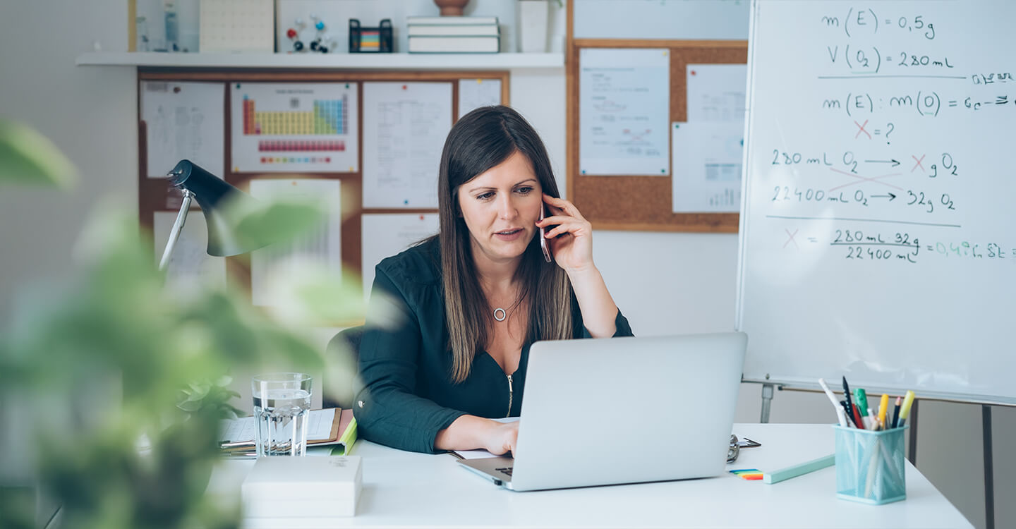 Woman at desk on phone and laptop