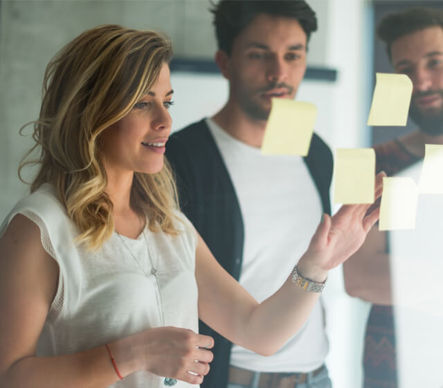 People adding post-its on a glass wall