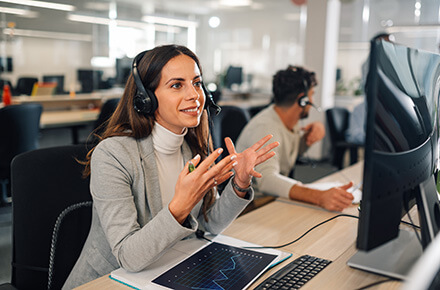 A woman on a phone in front of her monitor