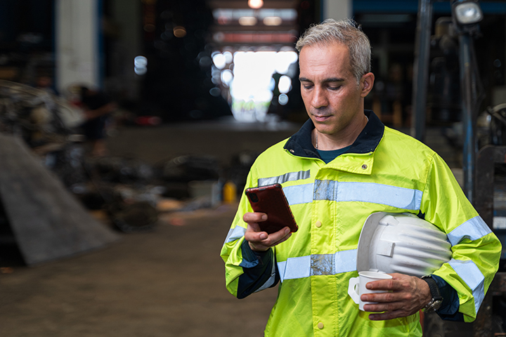 Man in hi-vis jacket on mobile with hard hat
