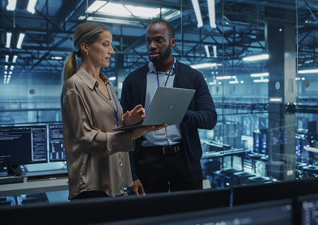 man and woman checking laptop in datacenter