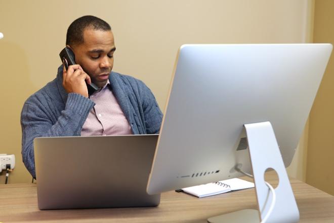 mitel-man-on-mitel-phone-at-desk-using-computer