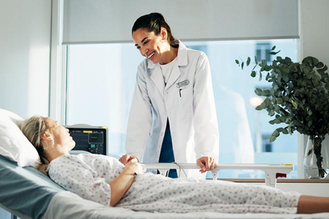 Healthcare professional standing by patient in bed