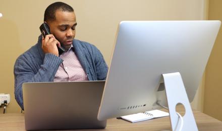 mitel-man-on-mitel-phone-at-desk-using-computer